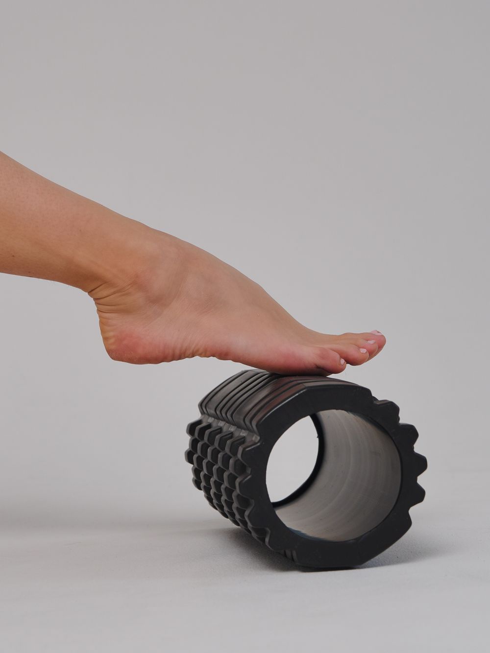 Black textured hollow foam roller shown in use