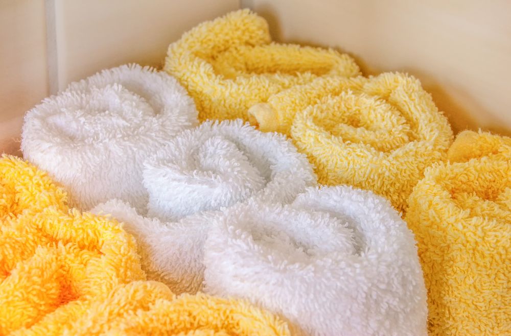 Rolled white and yellow spa towels with visible looped texture